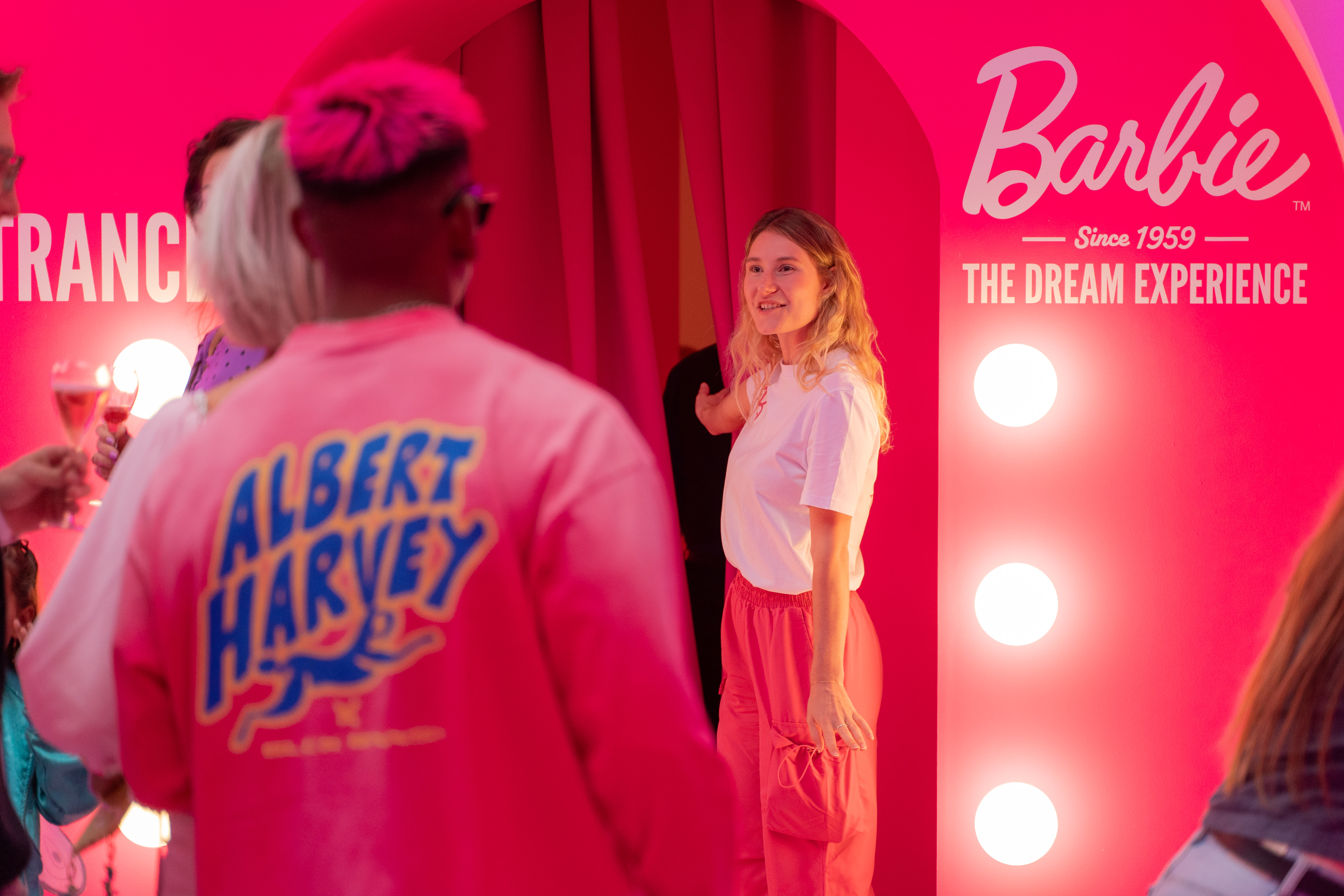 woman-opening-curtain-for-people-to-enter-barbie-experience-museum