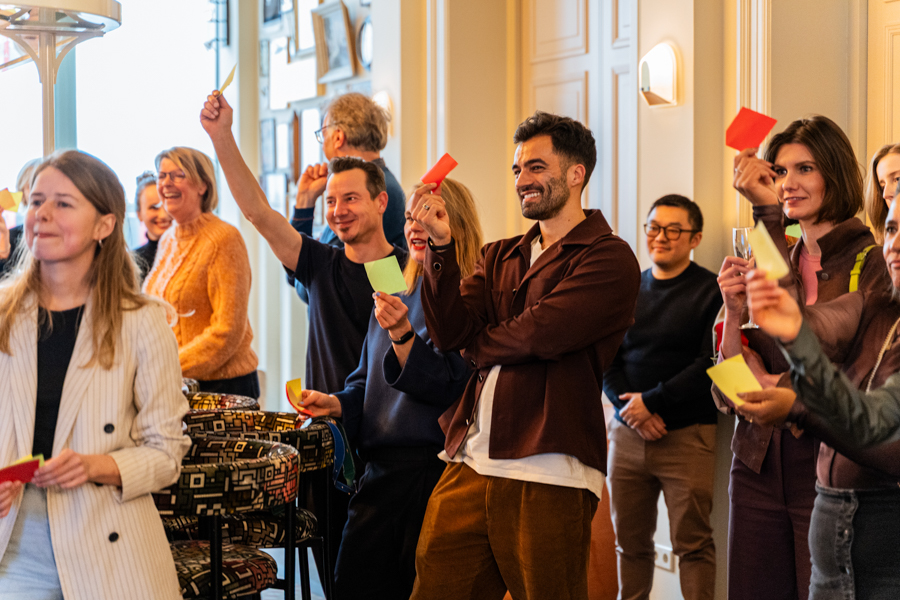 Mensen die in een groep staan ​​en tijdens een evenement papieren in verschillende kleuren omhooghouden.