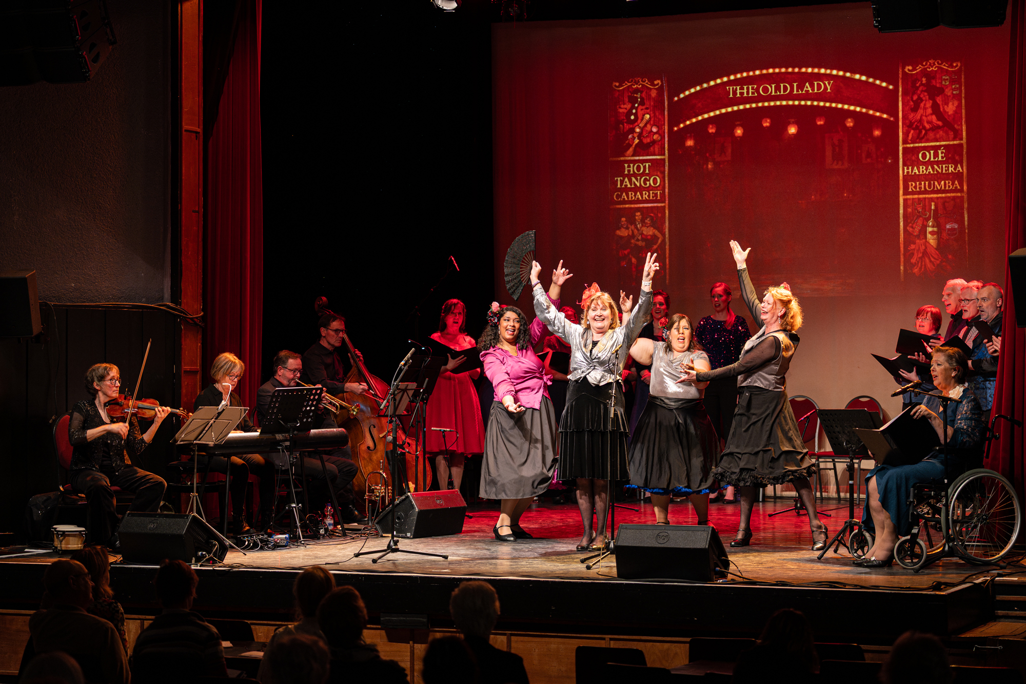 Theatre performance orchestra and women posing on stage