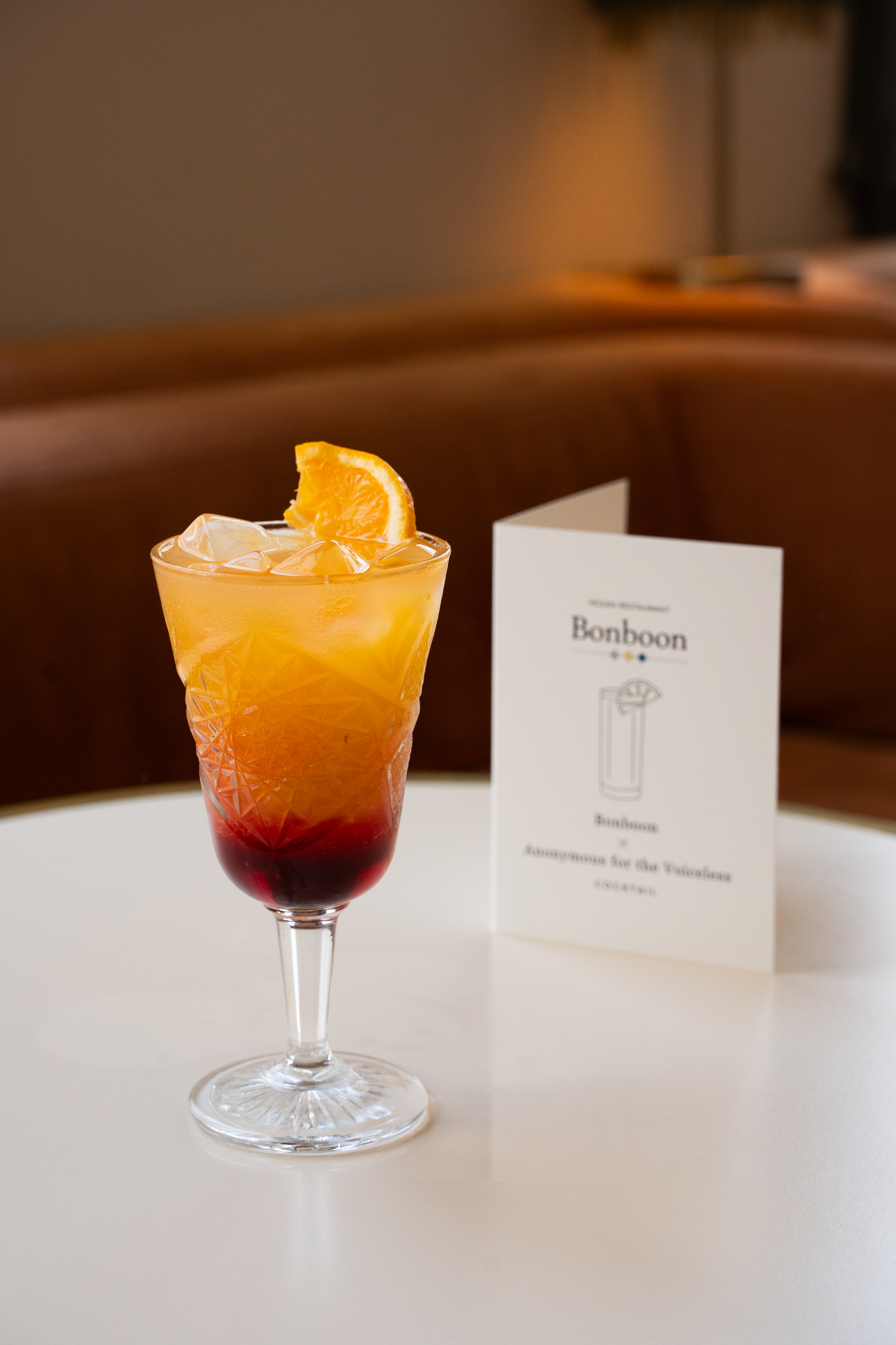 Cocktail sunrise on a white table net to a small menu card.