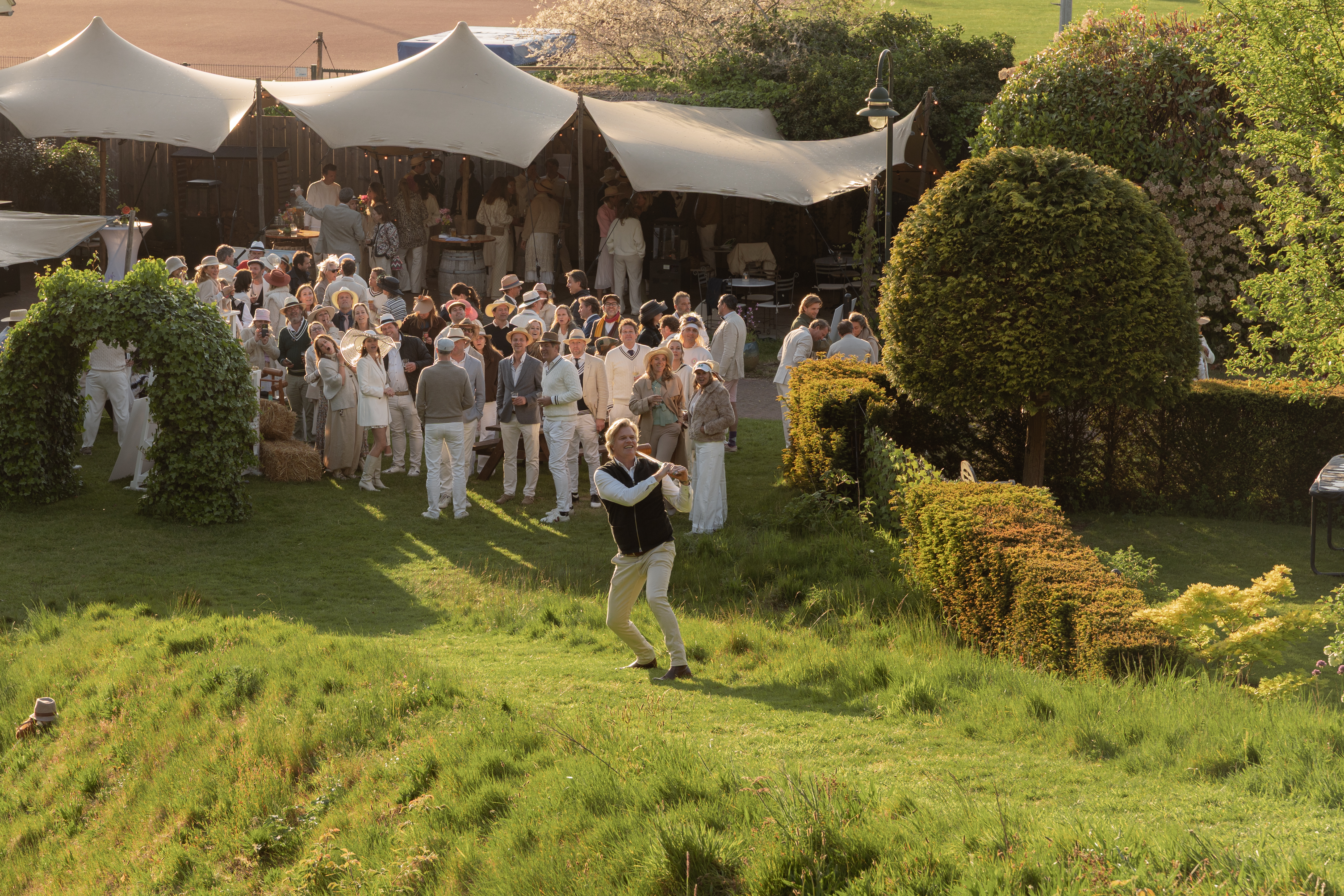 Man playing croquet while group watching him.
