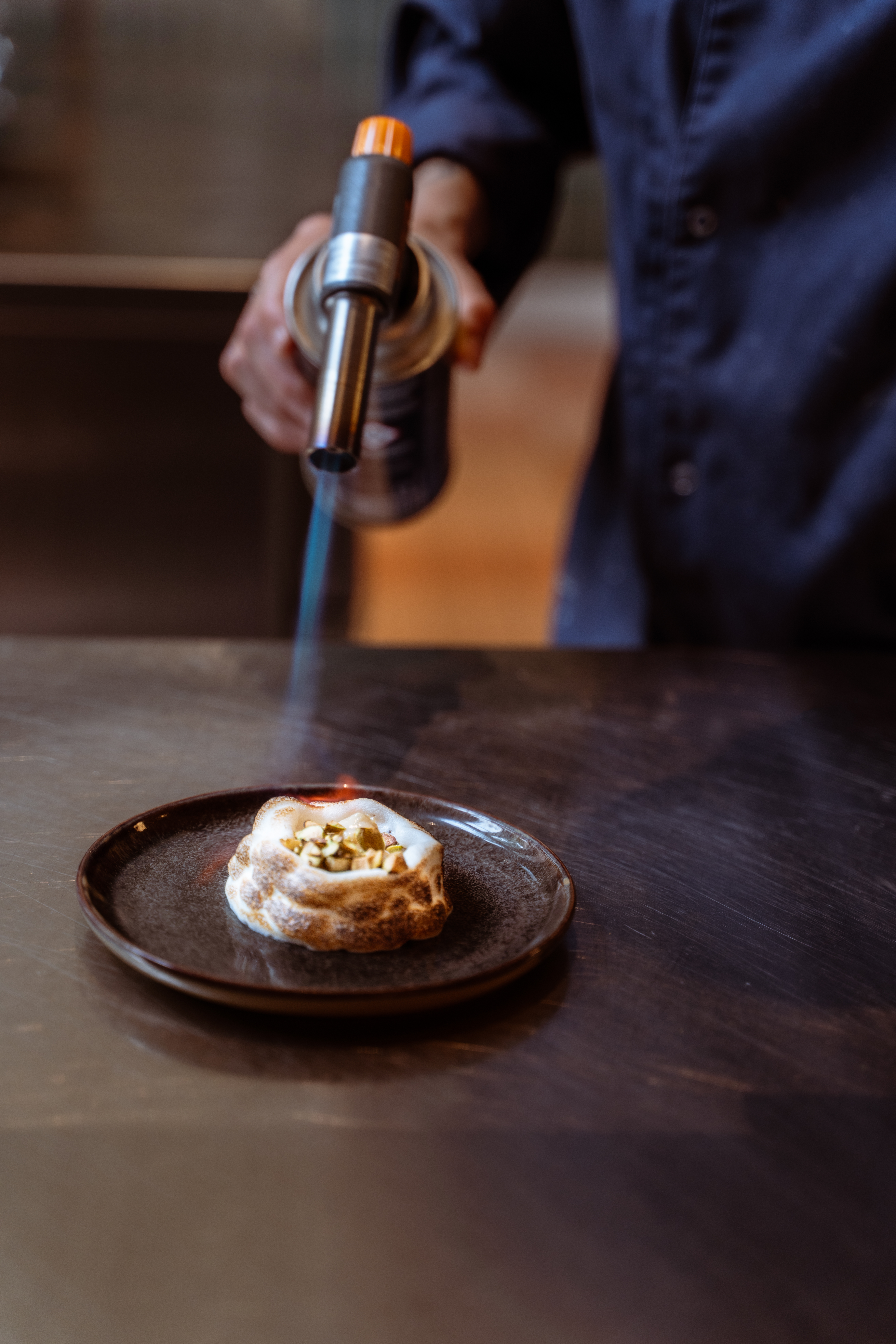 Chef using a burner to color the dessert.