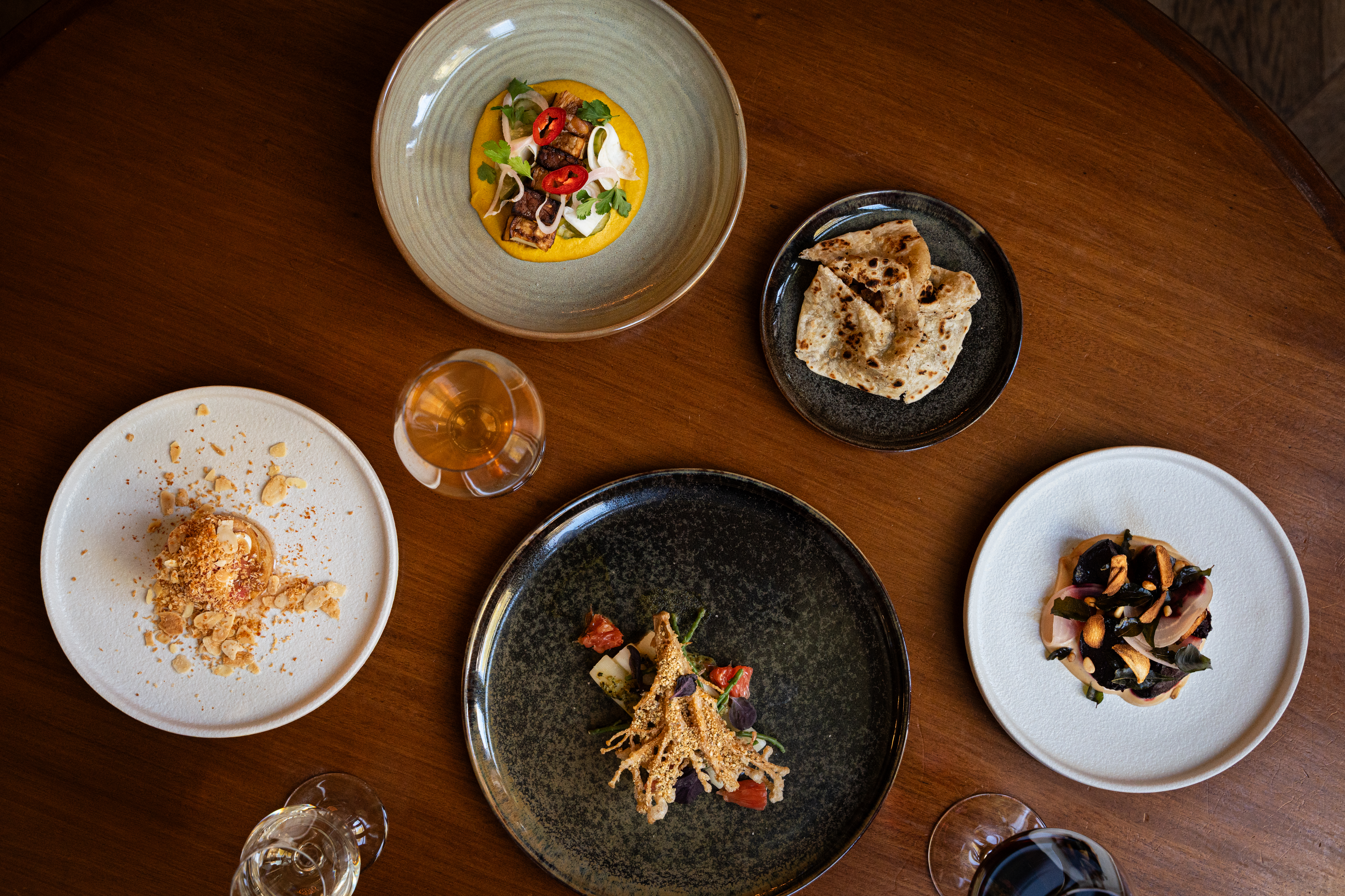 Food photography top angle of four different dishes and three different type of wine in glasses.